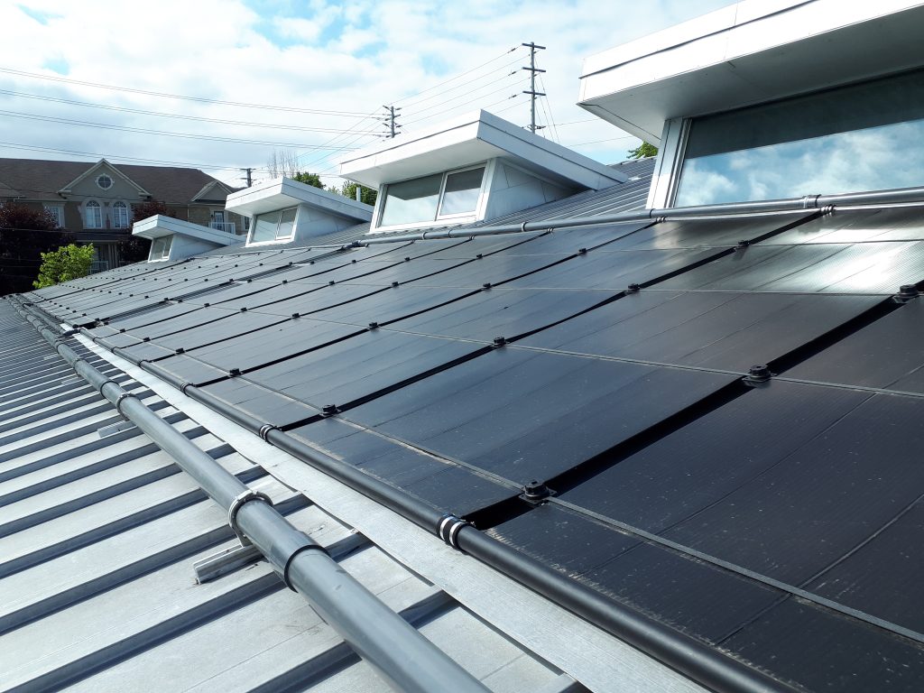 side angled shot of solar pool heating array on roof of outdoor public swimming pool facilities